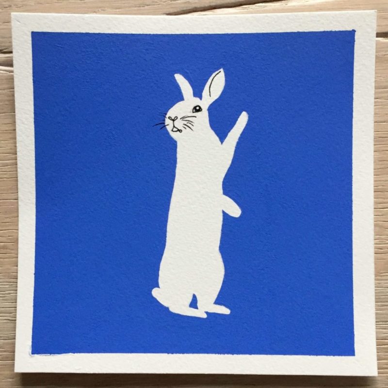 Gouache illustration of a white rabbit on a smalt blue background.